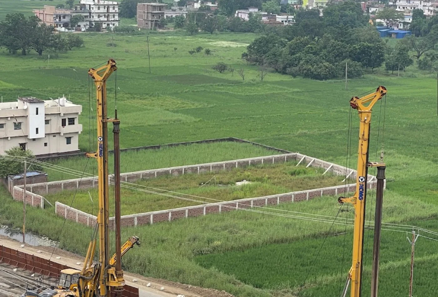 Piling equipment working beside field-side development land and utility corridors